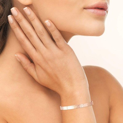 Bracelet jonc Ethnéa plaqué or rose porté au poignet d'une femme, motif tribal texturé visible, style chic