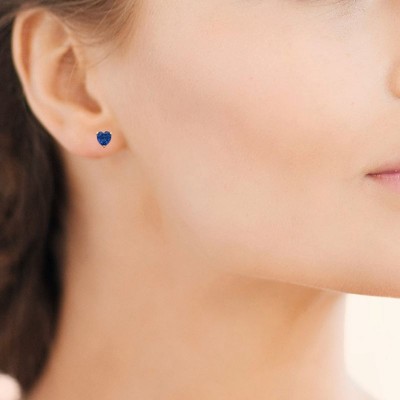 modèle femme portant des boucles d'oreilles coeur pierre bleue